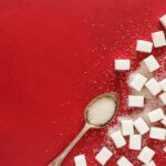 sugar cubes and a spoon on a red surface