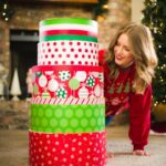 a woman leaning over a stack of christmas presents