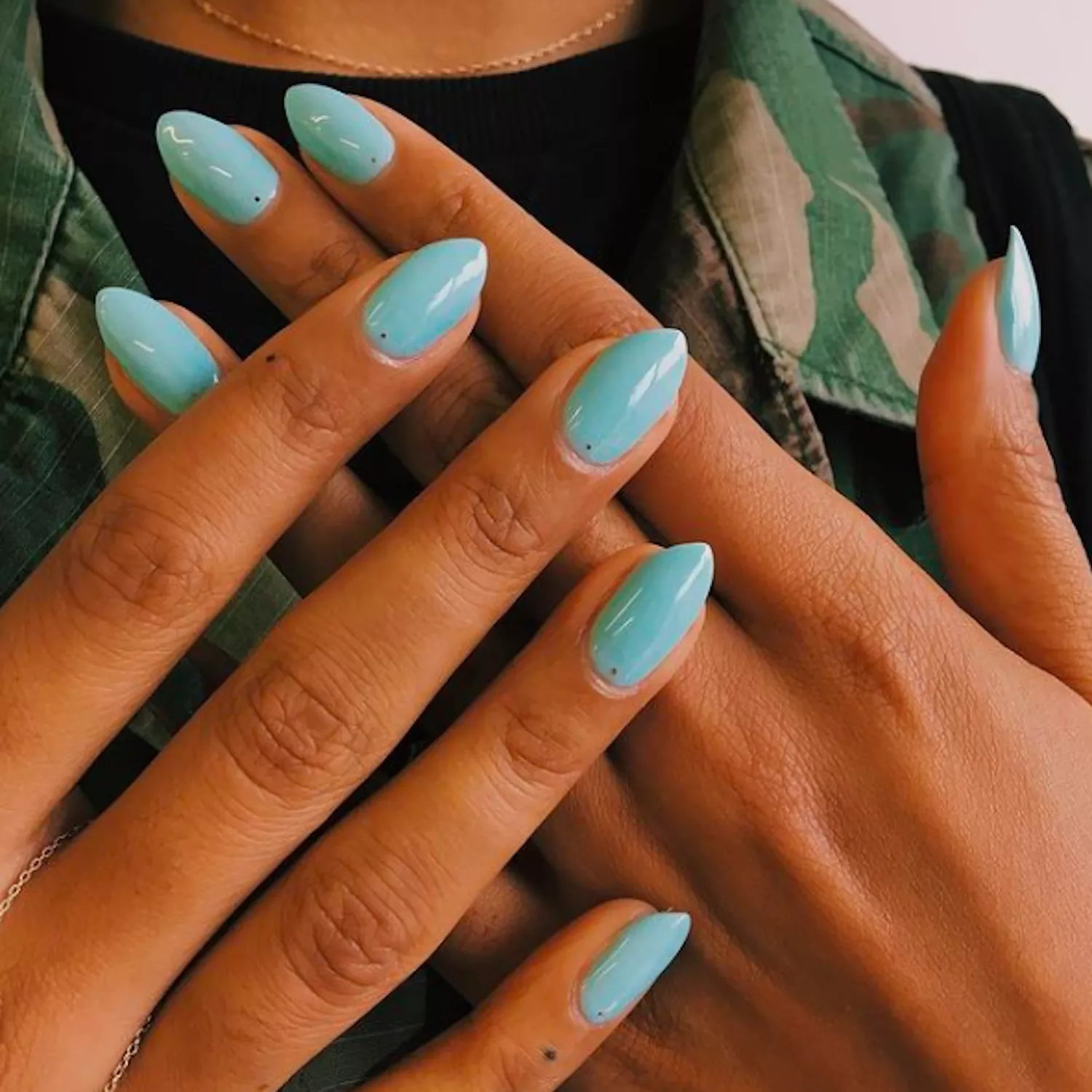 baby blue manicure with tiny black dot detail at base of nail