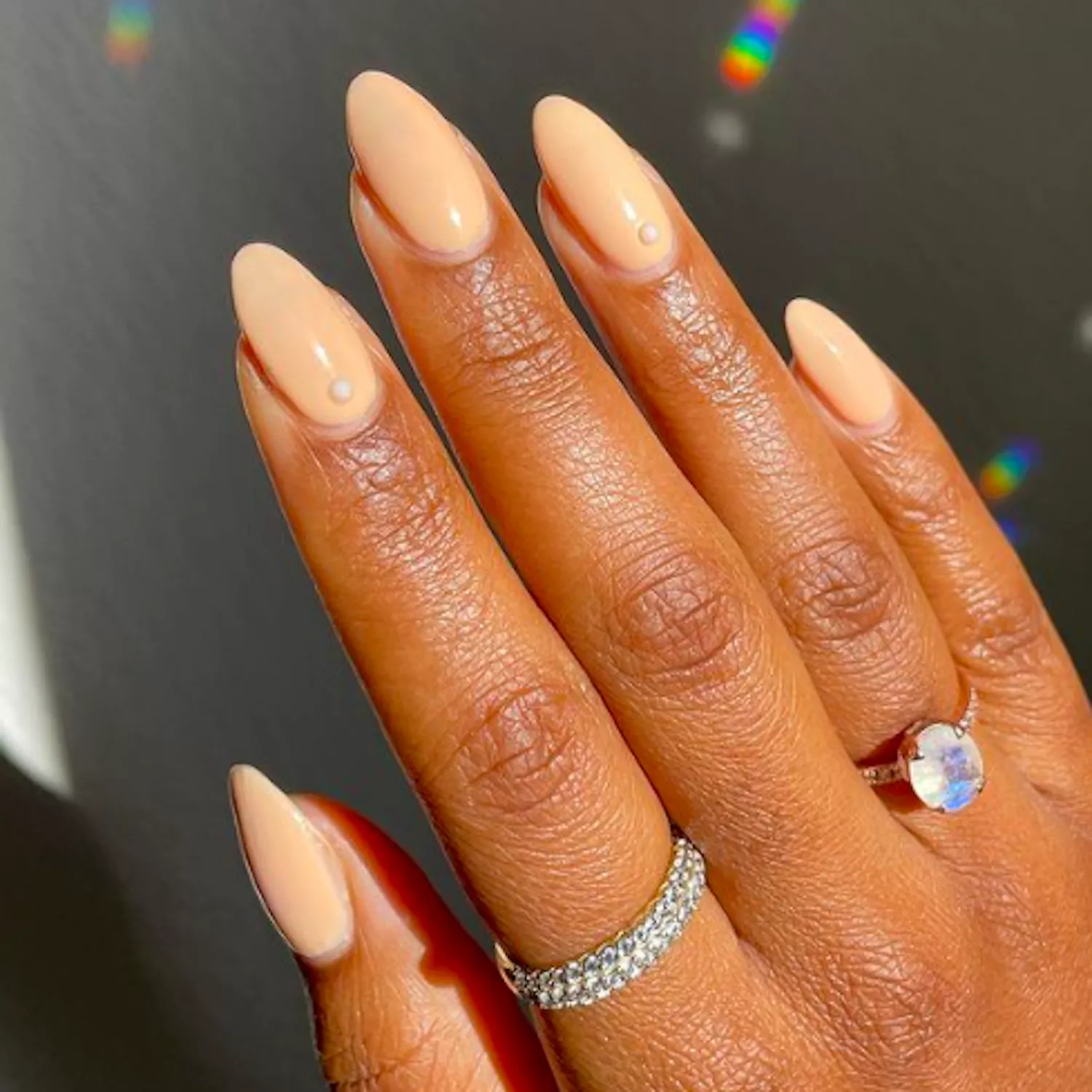 peach almond nails with pearl design at the base of the nail