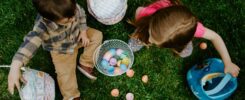 girl in green jacket playing with white and pink plastic balls on green grass field during