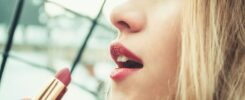 selective focus photography of woman holding lipstick