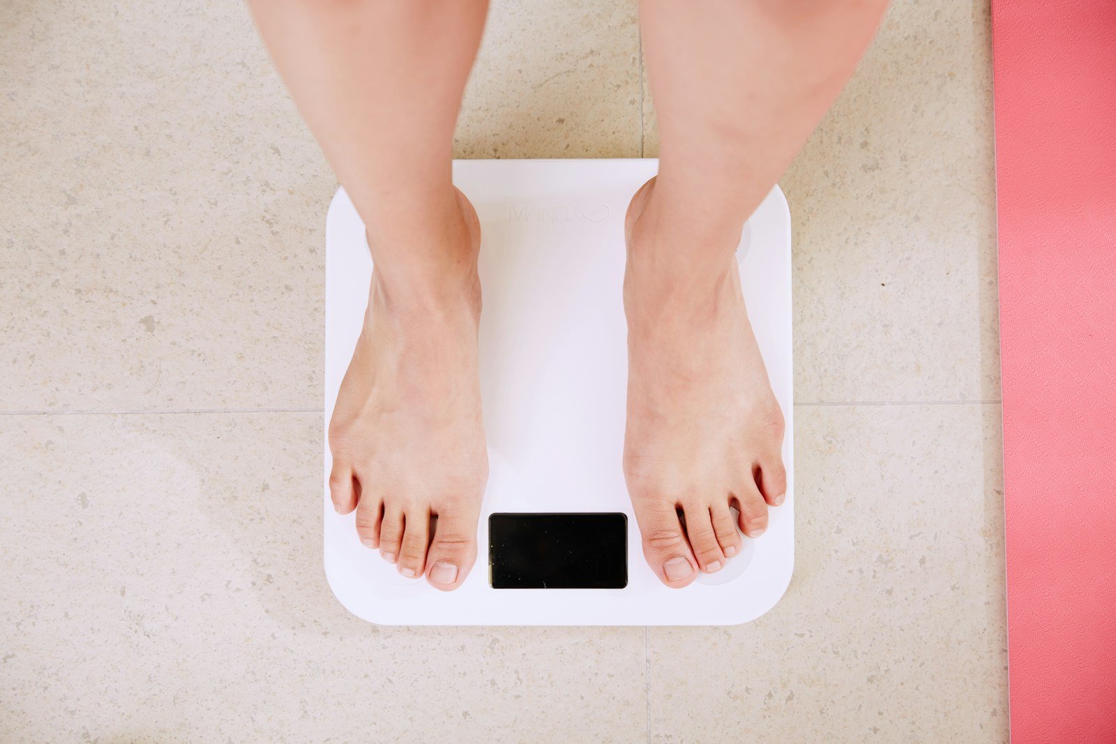 14 Simple and Natural Ways to Increase Your Weight Safely and Effectively person standing on white digital bathroom scale