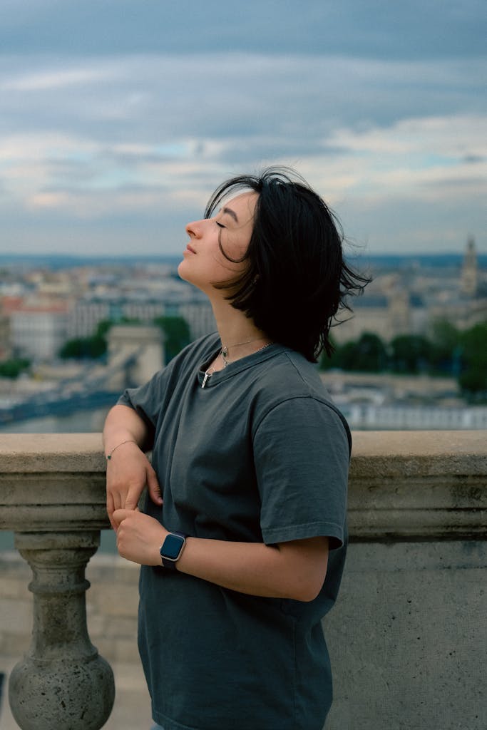 A woman enjoying a serene moment outdoors with a cityscape in the background.