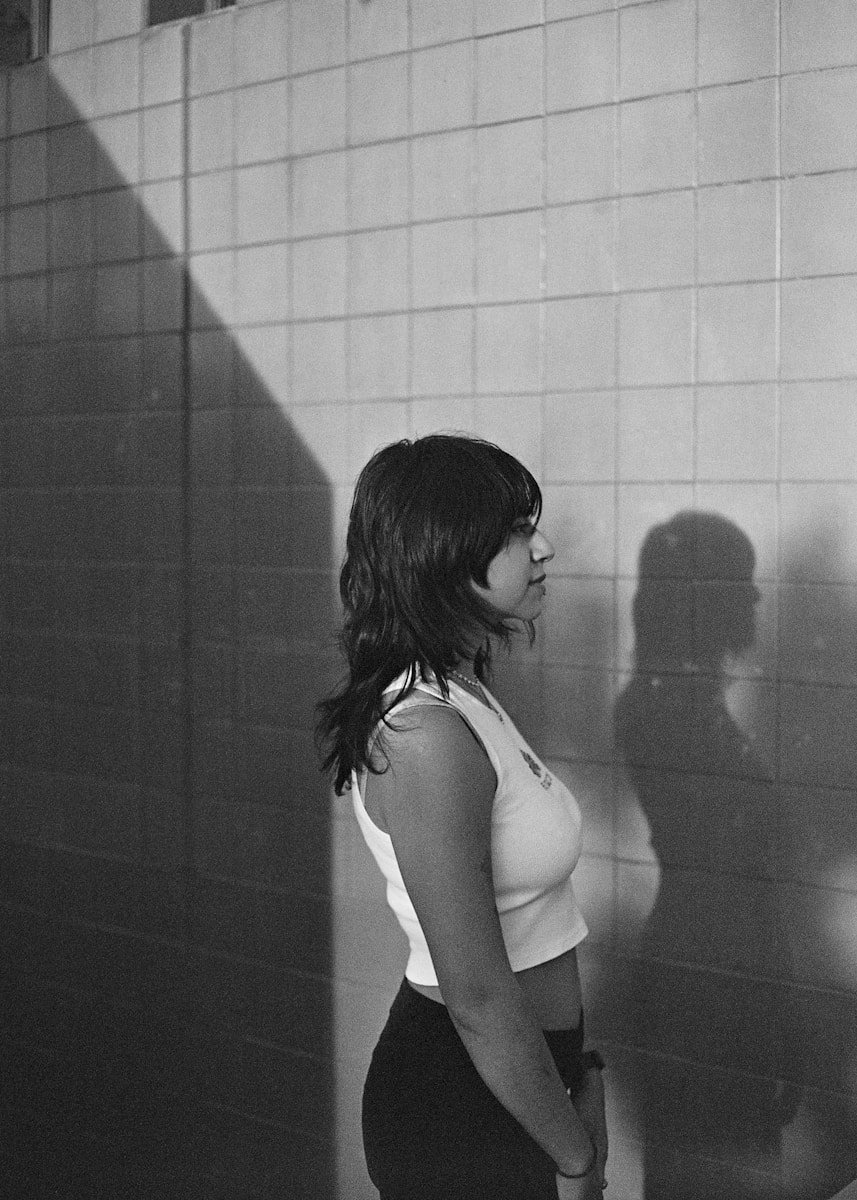 A black and white photo of a woman standing in front of a wall