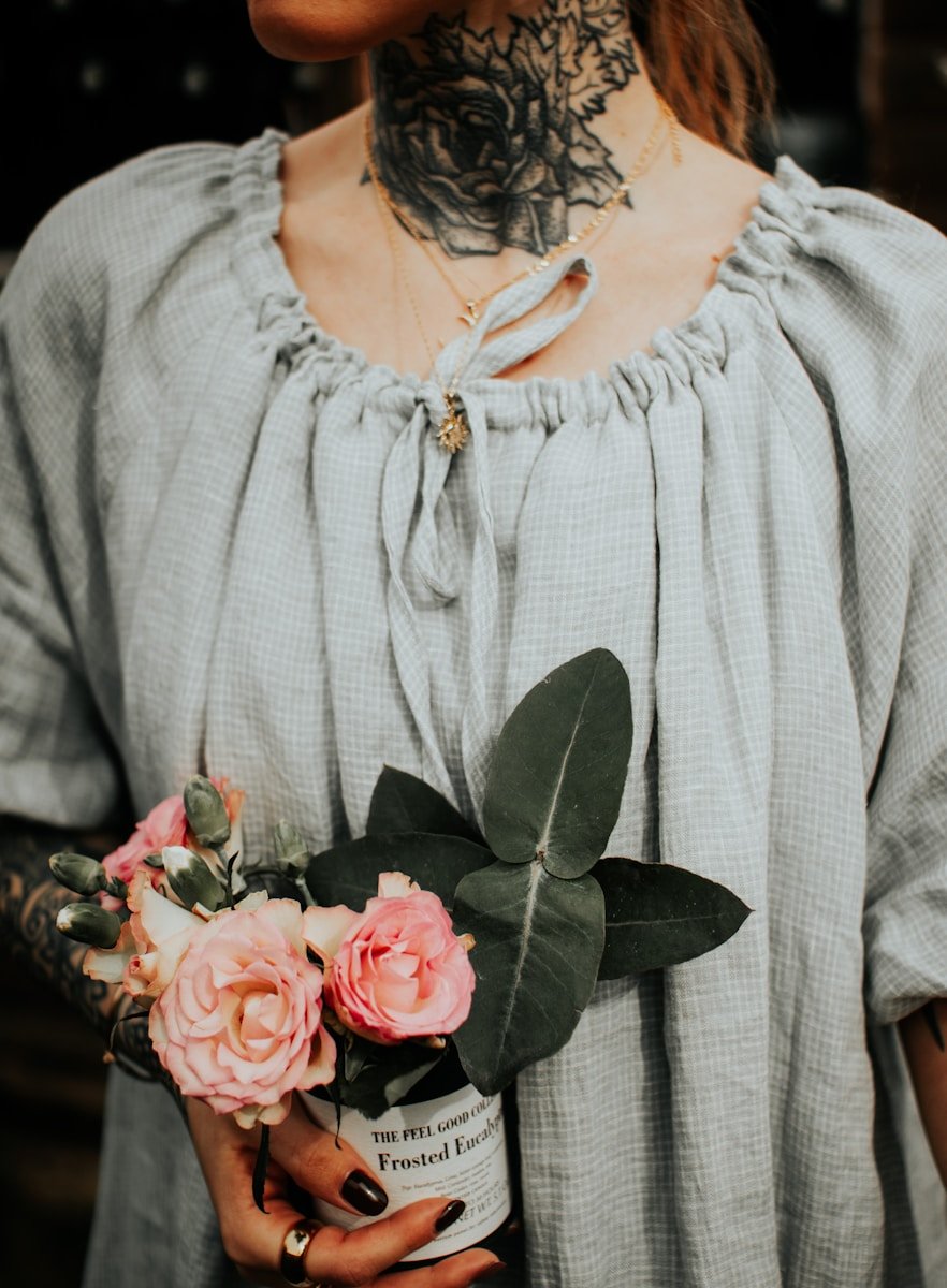 a tattooed woman holding a bouquet of flowers