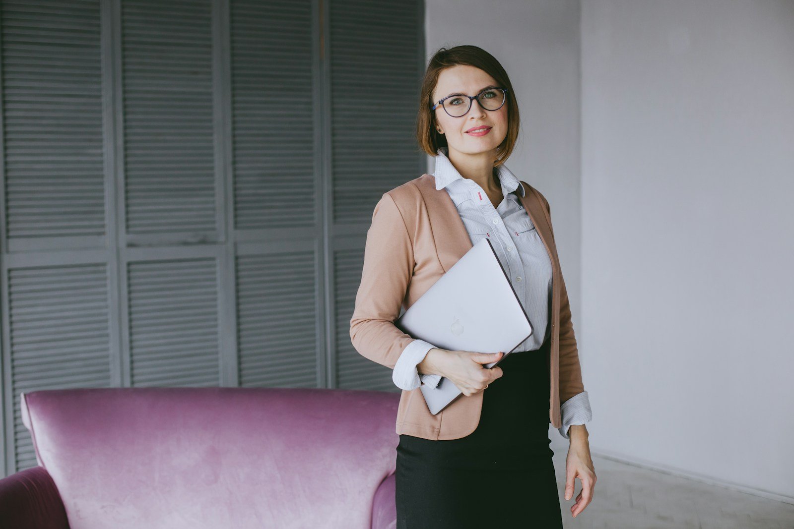 a woman in a business suit holding a laptop