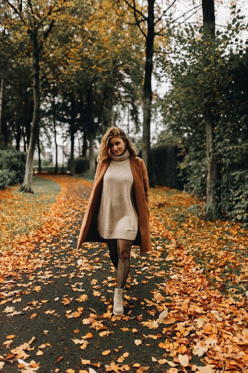 a woman walking down a leaf covered road