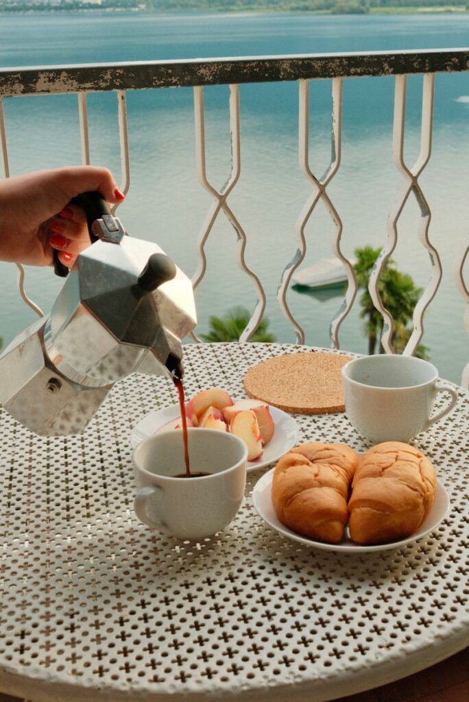 A person pouring tea on a table with a view of the ocean