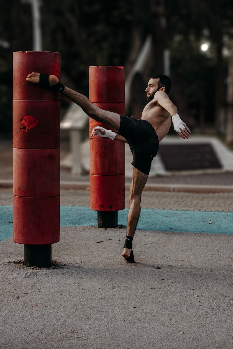 A man doing a kickbox kick in a park