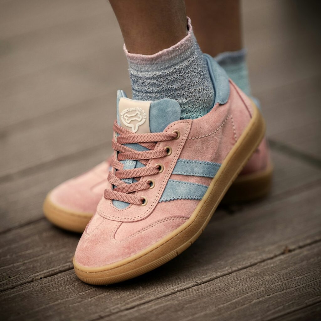 Pink sneakers are showcased against a wooden background.
