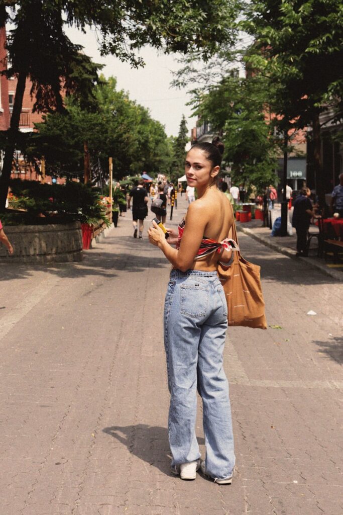 a woman standing on the side of a road looking at her cell phone