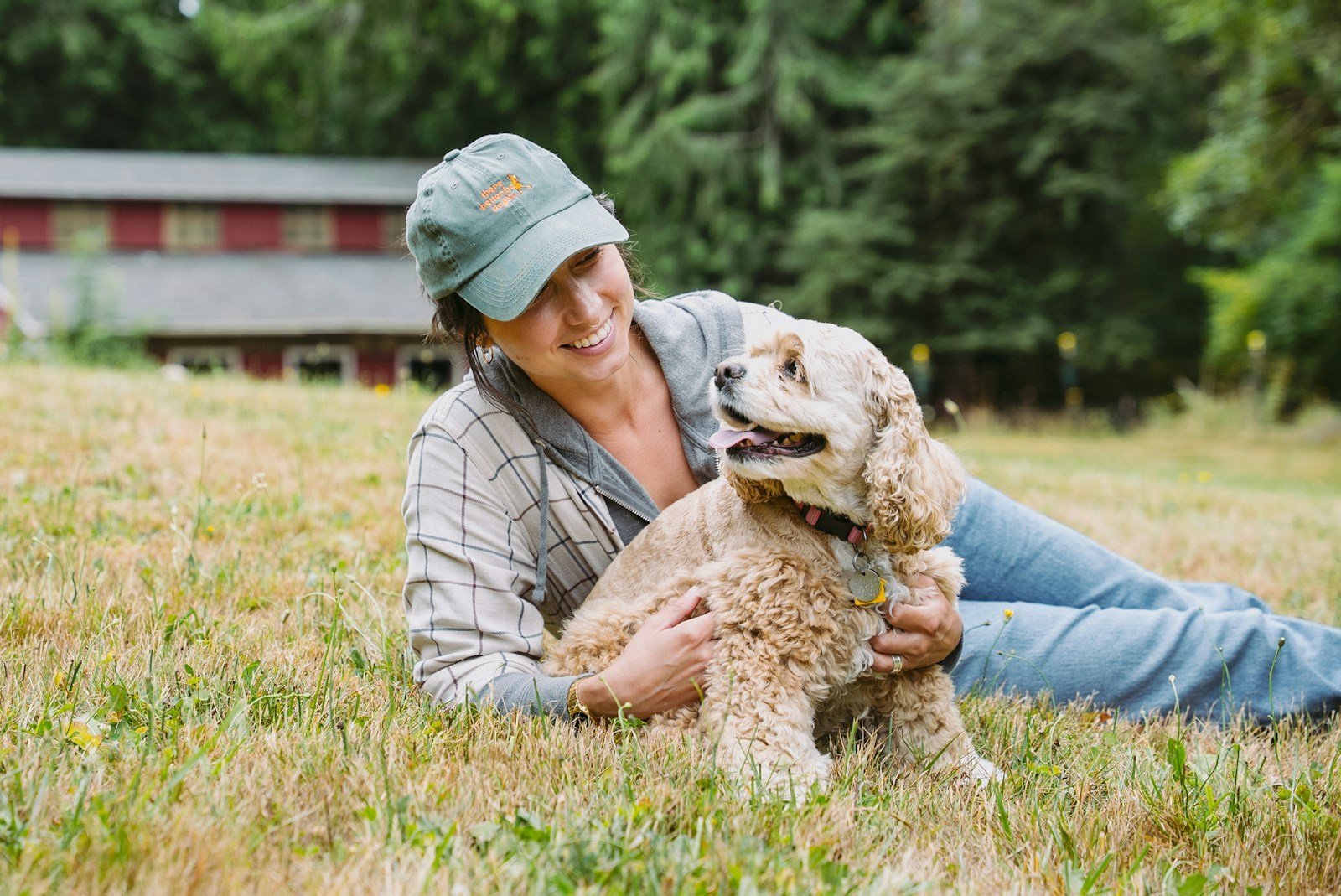 Woman pets her dog while relaxing on the grass.