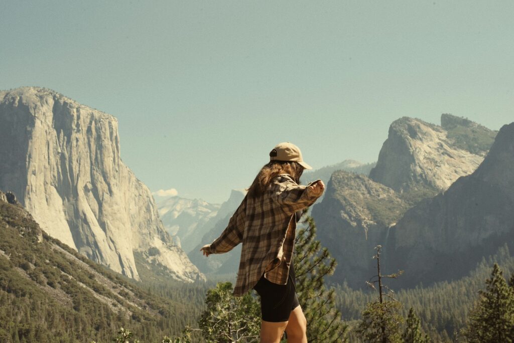 Woman in flannel overlooks yosemite valley mountains