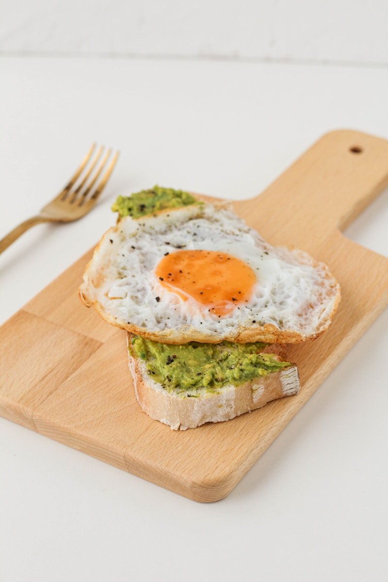 bread with sunny side up egg on brown wooden chopping board