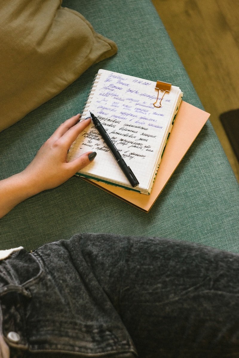 a person writing on a notebook with a pen