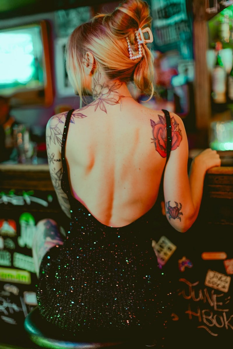 A woman sitting at a bar with a tattoo on her back