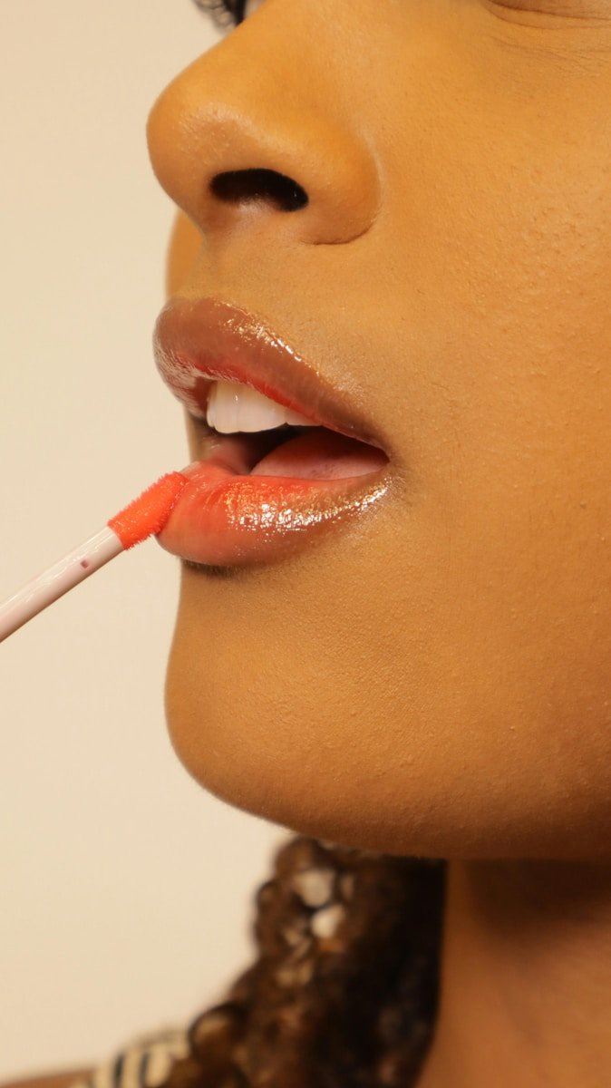 Applying lip gloss to lips.