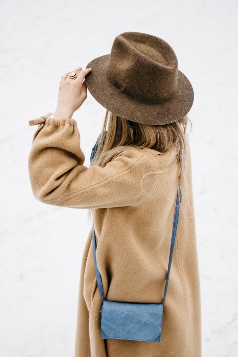 How to Stay Warm Without Sacrificing Style This Winter 2026 woman holding her hat