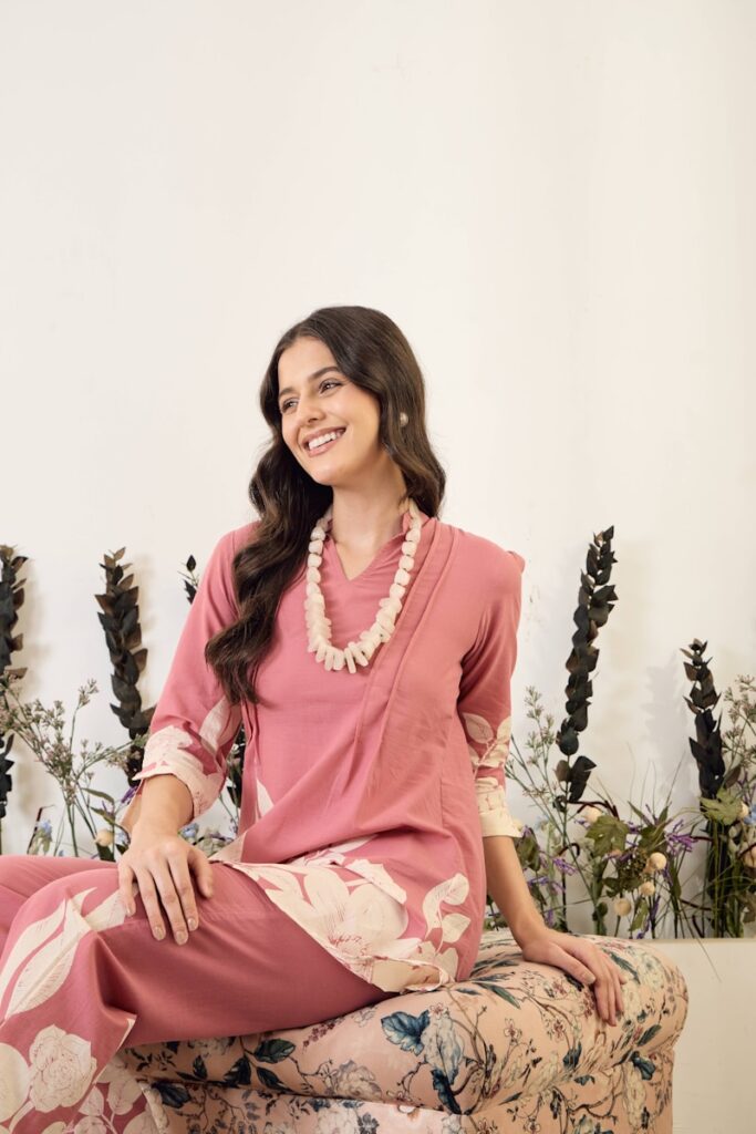 Woman in pink floral outfit with beaded necklace