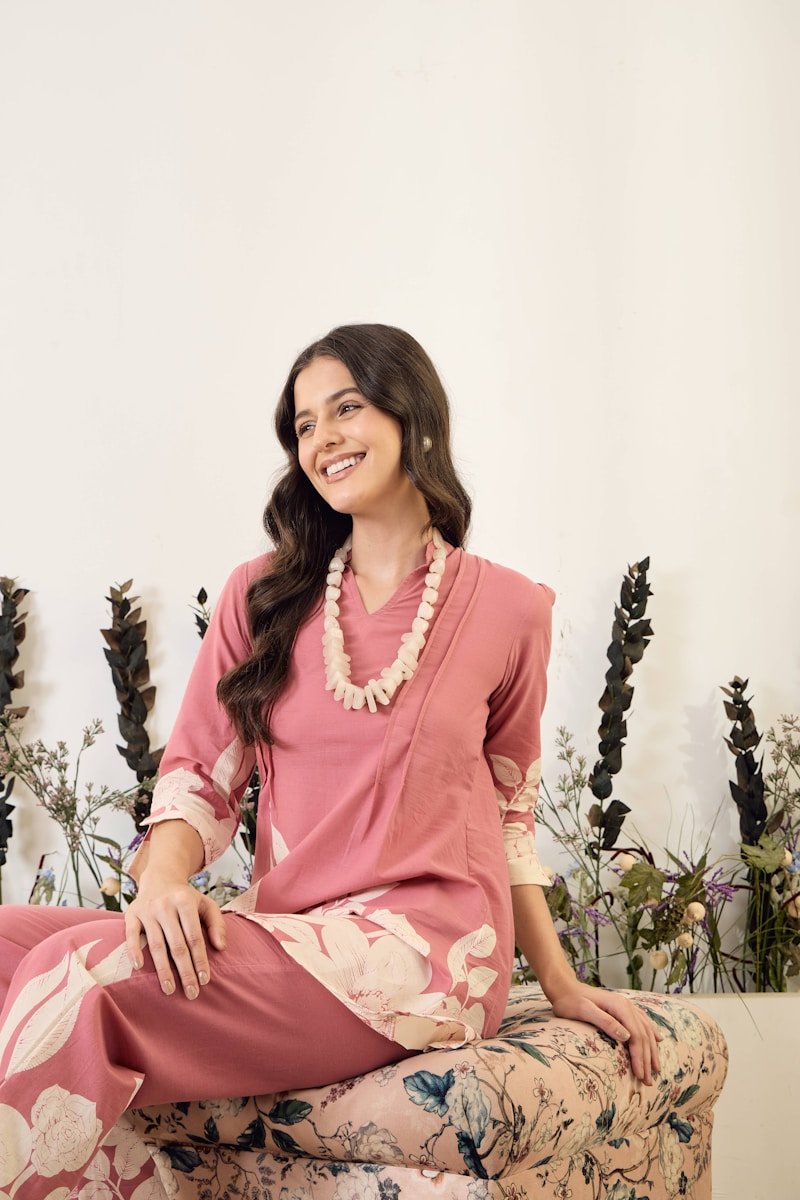 17 Wedding Guest Outfit Ideas Using Dresses You Already Own Woman in pink floral outfit with beaded necklace