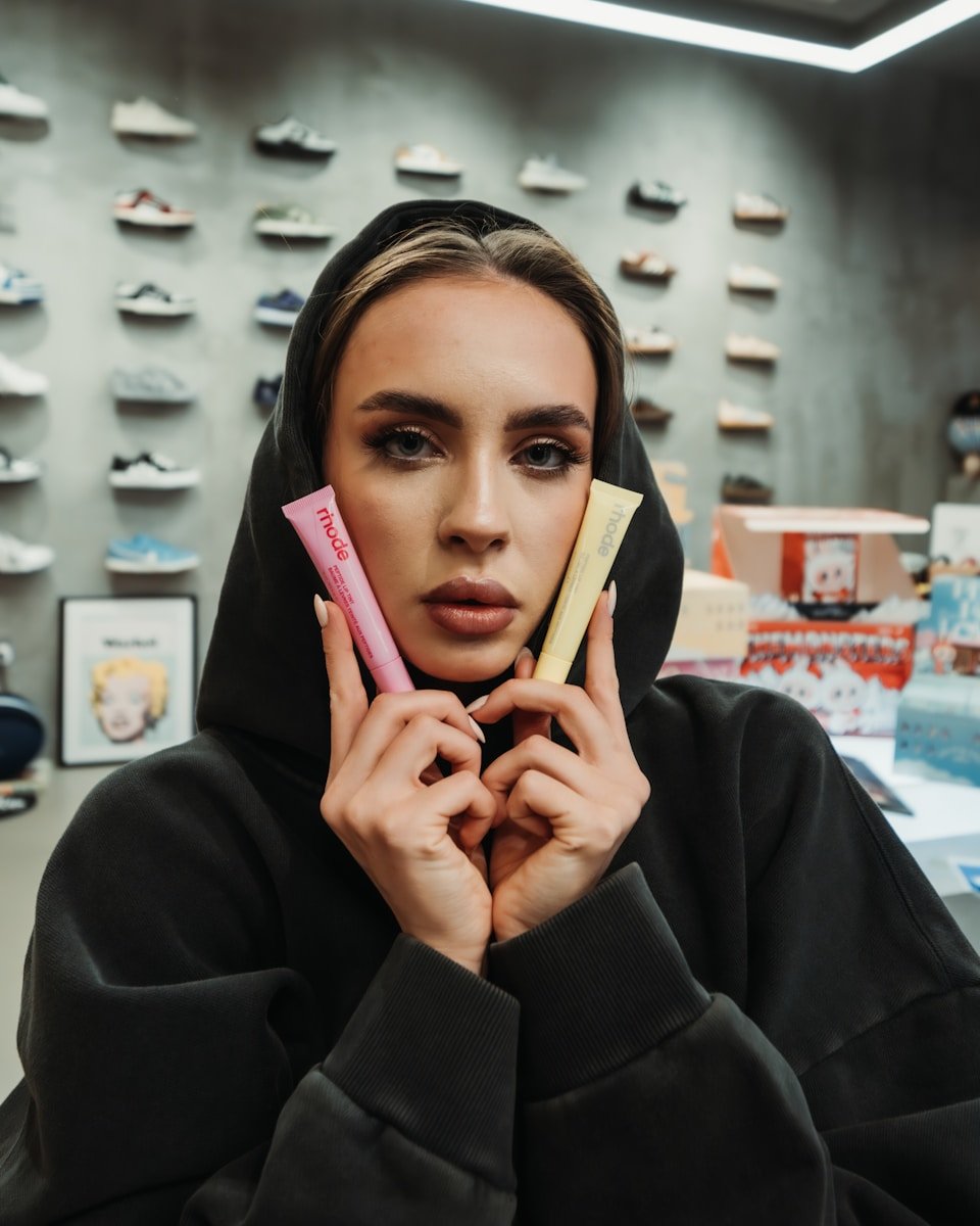 Korean Skincare Routine for Acne-Prone Skin That Still Gives Glass Skin Woman in hoodie holds pink and yellow tubes