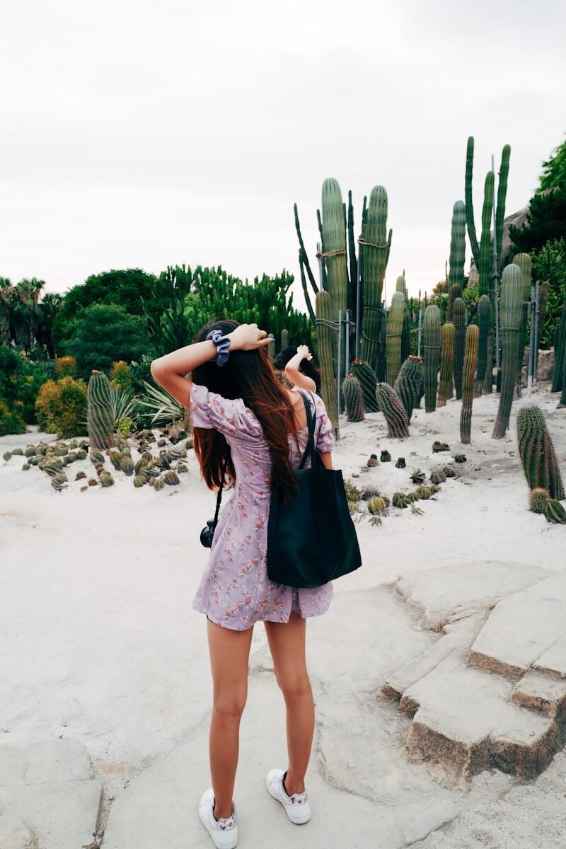 30 Summer Vacation Outfits That Are Perfect for Travel Photos woman in purple dress standing on beach during daytime