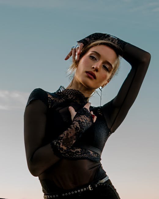 Striking outdoor portrait of a woman in black lace attire against a clear sky.
