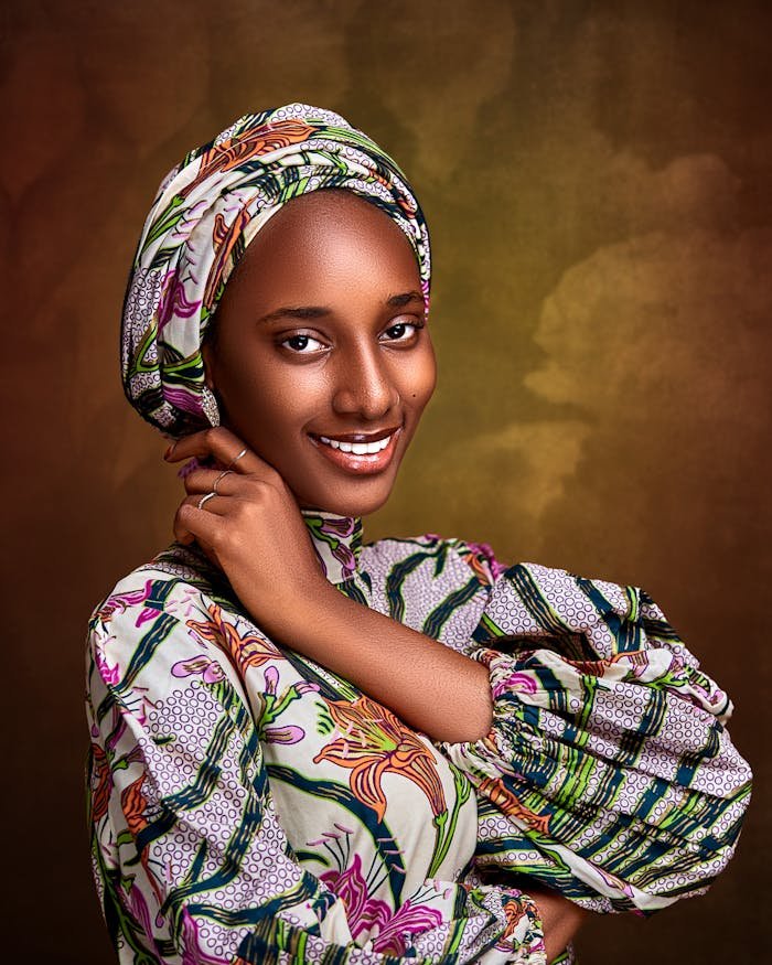 Captivating portrait of a smiling woman in traditional Nigerian attire against a warm backdrop.