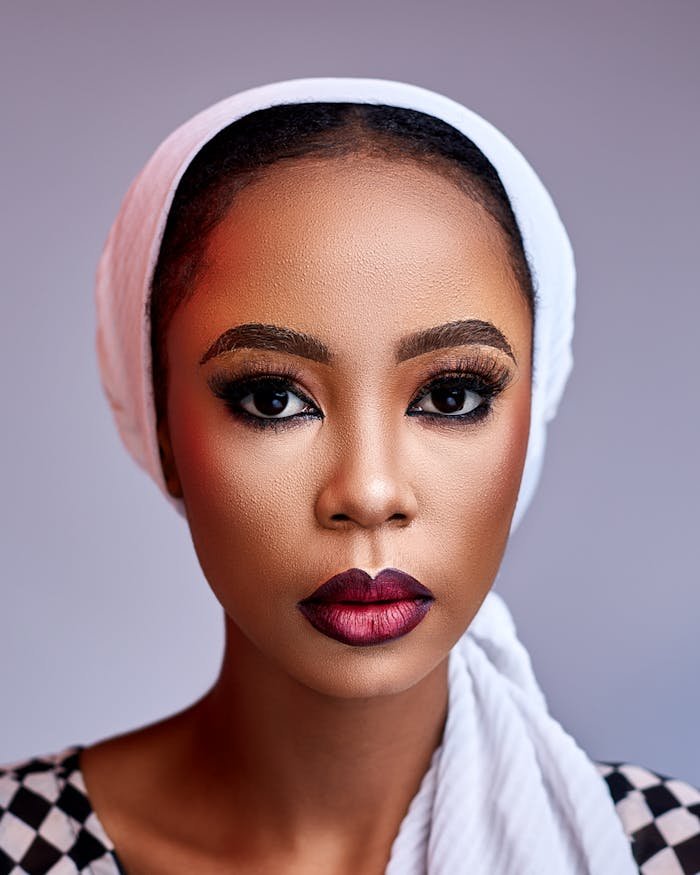 A striking portrait of a Nigerian woman with bold makeup and a headscarf, captured in vibrant detail.