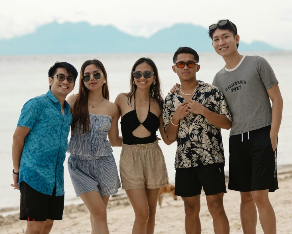 Five friends posing on a beach with mountains in background